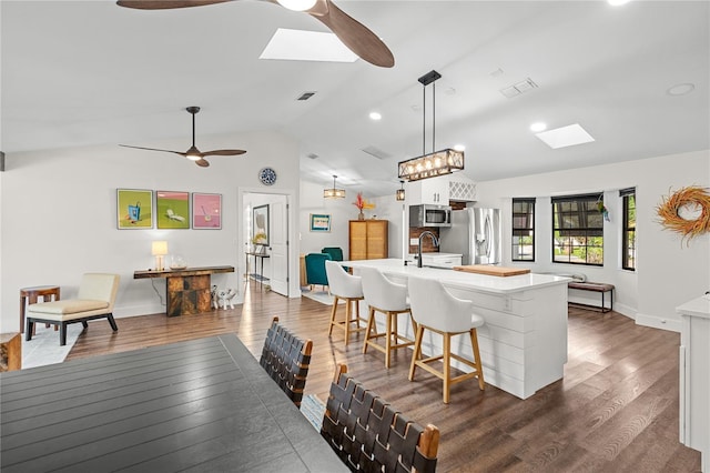 54 Fordham Ln, Palm Coast, FL 32137 - dining area featuring a ceiling fan, a skylight, lofted ceiling, dark wood-type flooring, and baseboards