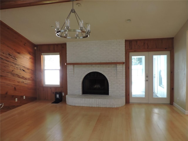 543 Sandy Oaks Blvd, Ormond Beach, FL 32174 - unfurnished living room with wooden walls, wood finished floors, a chandelier, french doors, and a brick fireplace