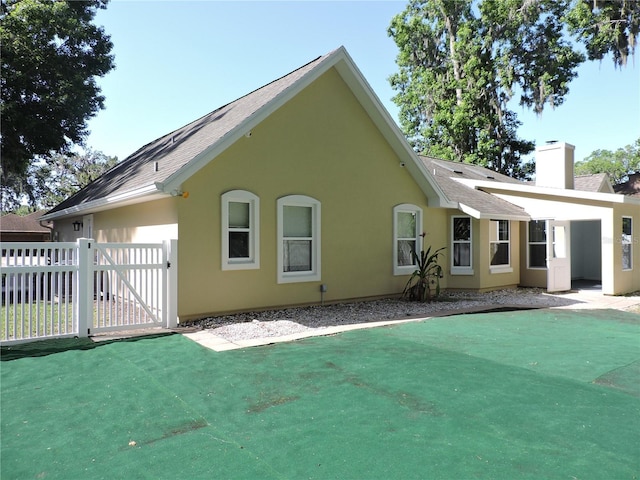 543 Sandy Oaks Blvd, Ormond Beach, FL 32174 - back of property with a chimney, a gate, roof with shingles, and stucco siding