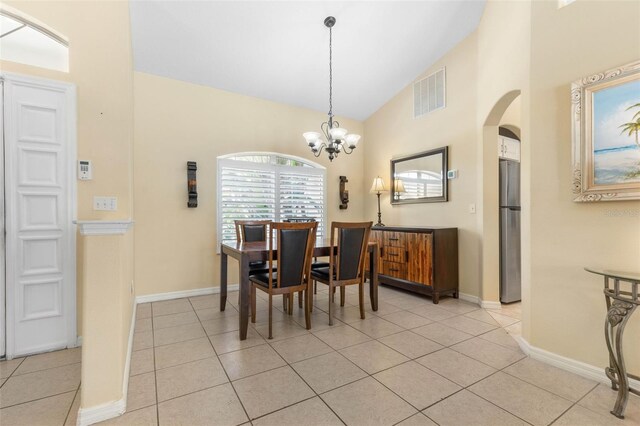 11 White Oak Ln, Palm Coast, FL 32164 - dining space featuring arched walkways, light tile patterned flooring, high vaulted ceiling, a chandelier, and baseboards