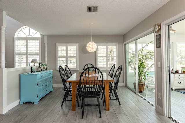 7 Bristol Dr, Palm Coast, FL 32137 - dining space with a chandelier, light wood-style floors, a textured ceiling, baseboards, and healthy amount of natural light