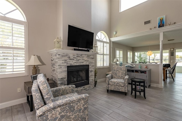 7 Bristol Dr, Palm Coast, FL 32137 - living room featuring a stone fireplace, wood finished floors, baseboards, and a high ceiling