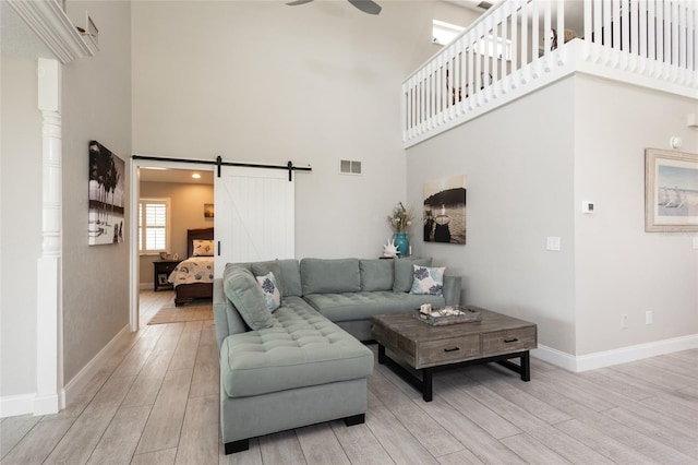 7 Bristol Dr, Palm Coast, FL 32137 - living room featuring a high ceiling, light wood-style flooring, ceiling fan, baseboards, and a barn door