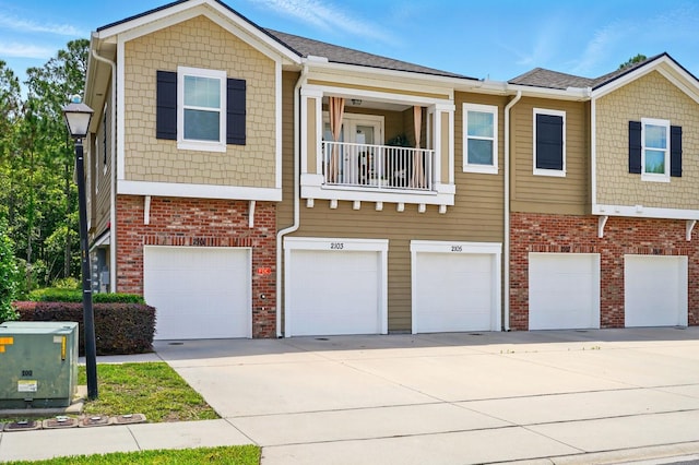 townhome / multi-family property with a garage, driveway, and brick siding