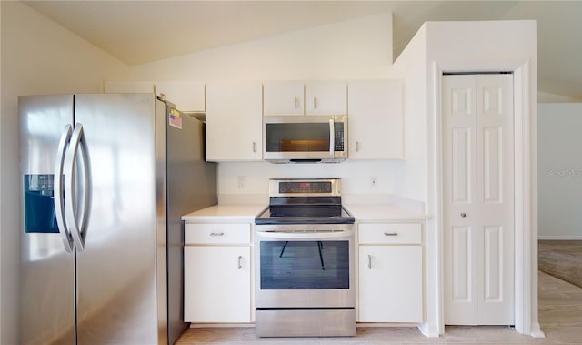 kitchen featuring appliances with stainless steel finishes, lofted ceiling, light countertops, and white cabinetry