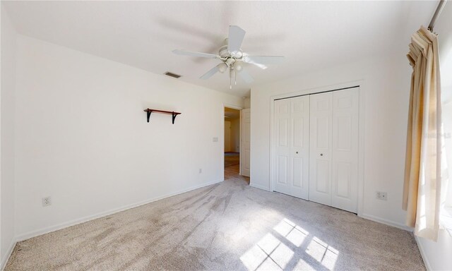 unfurnished bedroom featuring carpet, baseboards, a closet, and ceiling fan