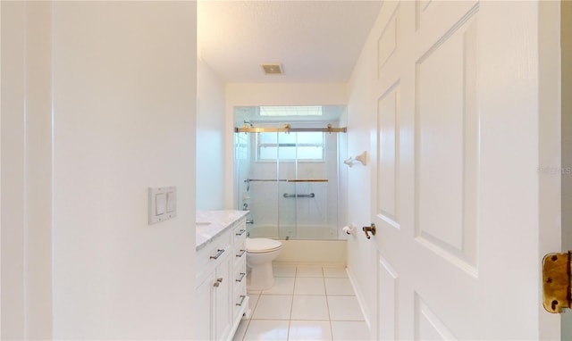 bathroom with tile patterned floors, enclosed tub / shower combo, vanity, and toilet