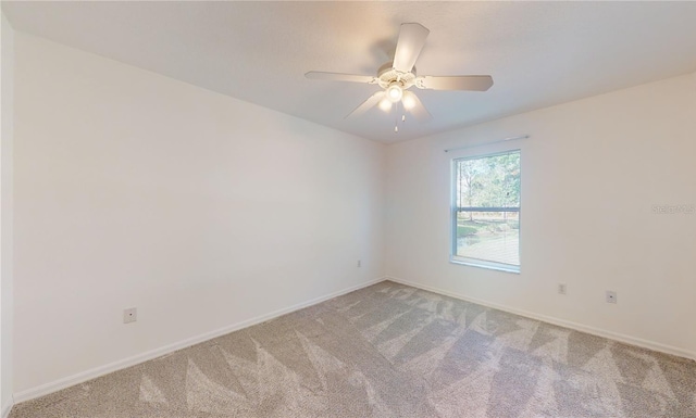 spare room featuring light carpet, baseboards, and a ceiling fan