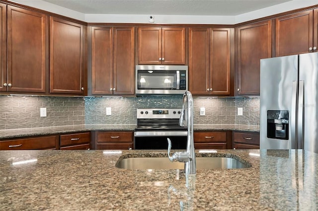 40 Oakleaf Way, Palm Coast, FL 32137 - kitchen featuring appliances with stainless steel finishes, dark stone countertops, a sink, and decorative backsplash