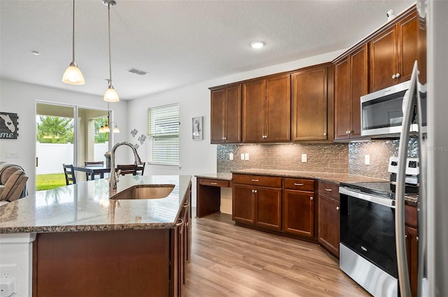 40 Oakleaf Way, Palm Coast, FL 32137 - kitchen featuring appliances with stainless steel finishes, a sink, light stone countertops, light wood-type flooring, and decorative backsplash