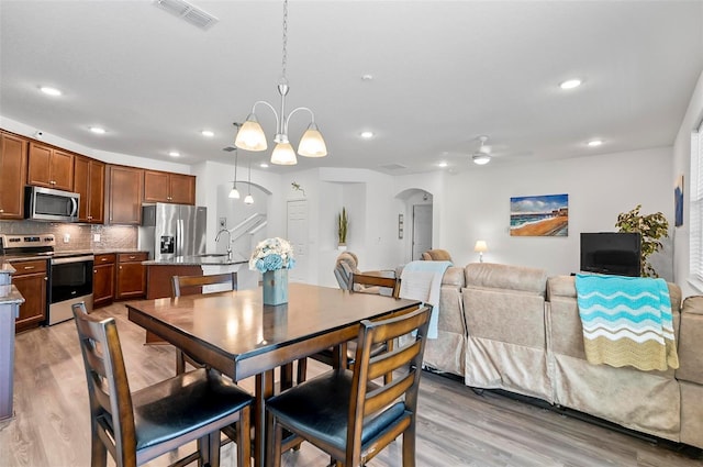 40 Oakleaf Way, Palm Coast, FL 32137 - dining space featuring arched walkways, light wood-style floors, recessed lighting, a chandelier, and ceiling fan