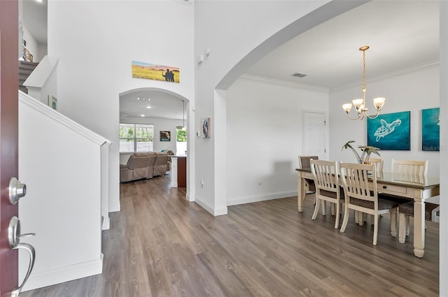 40 Oakleaf Way, Palm Coast, FL 32137 - dining area with arched walkways, wood finished floors, a chandelier, baseboards, and a towering ceiling