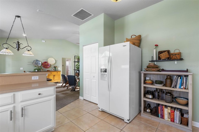 11 Roxboro Dr, Palm Coast, FL 32164 - kitchen with white fridge with ice dispenser, lofted ceiling, light tile patterned floors, white cabinets, and hanging light fixtures