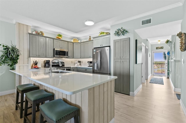 80 Surfview Dr Unit 721, Palm Coast, FL 32137 - kitchen featuring gray cabinets, a kitchen bar, a peninsula, appliances with stainless steel finishes, and light wood-type flooring
