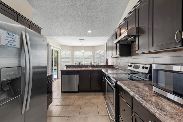 7 White Oak Ln, Palm Coast, FL 32164 - kitchen with stainless steel appliances, under cabinet range hood, dark countertops, a sink, and a textured ceiling