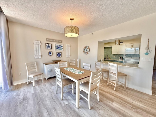 1601 N Central Ave Unit G10, Flagler Beach, FL 32136 - dining space featuring light wood finished floors, a textured ceiling, and baseboards