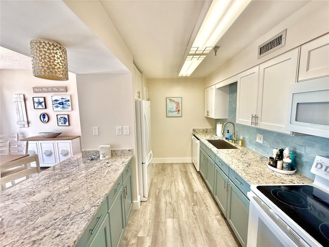 1601 N Central Ave Unit G10, Flagler Beach, FL 32136 - kitchen featuring white appliances, a sink, green cabinetry, light wood finished floors, and tasteful backsplash