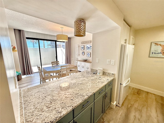 1601 N Central Ave Unit G10, Flagler Beach, FL 32136 - kitchen with freestanding refrigerator, baseboards, light wood finished floors, a peninsula, and light stone countertops