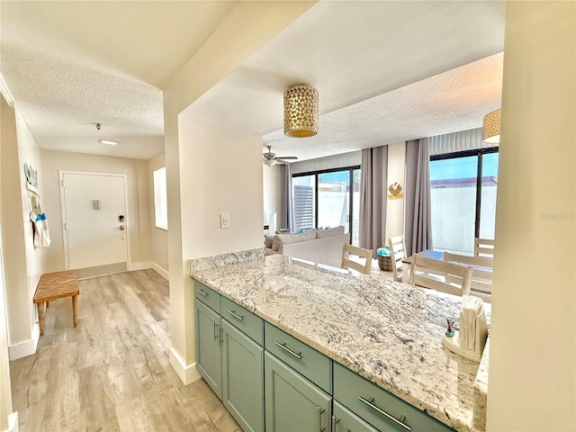 1601 N Central Ave Unit G10, Flagler Beach, FL 32136 - kitchen with green cabinetry, a textured ceiling, light wood-type flooring, baseboards, and open floor plan