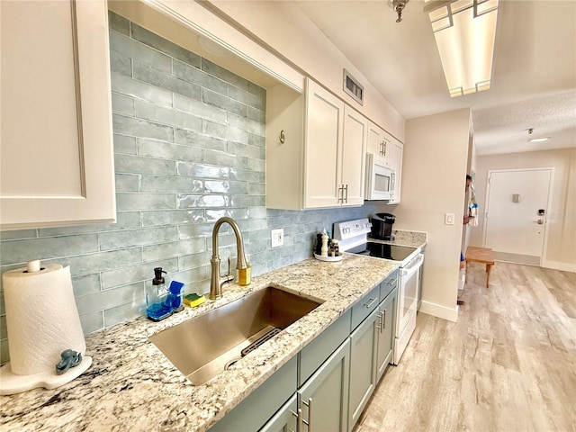 1601 N Central Ave Unit G10, Flagler Beach, FL 32136 - kitchen with white appliances, a sink, backsplash, light wood-style flooring, and light stone countertops