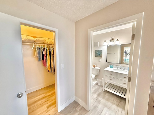 1601 N Central Ave Unit G10, Flagler Beach, FL 32136 - bathroom with wood finished floors, toilet, vanity, baseboards, and a textured ceiling