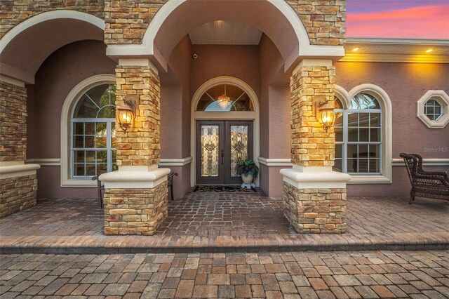 568 Luna Bella Ln, New Smyrna Beach, FL 32168 - doorway to property with french doors, stucco siding, and stone siding
