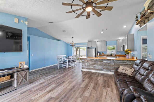 226 Pinegrove Dr, Palm Coast, FL 32164 - living room with vaulted ceiling, wood finished floors, ceiling fan, baseboards, and recessed lighting