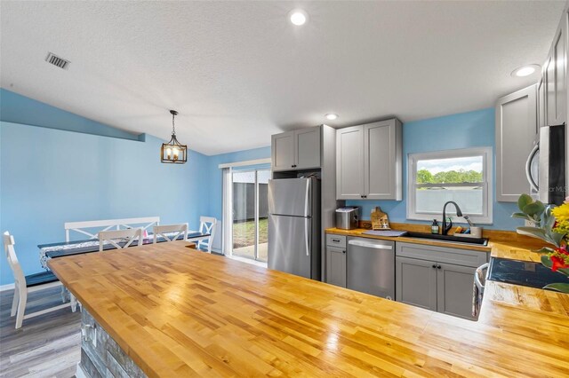226 Pinegrove Dr, Palm Coast, FL 32164 - kitchen featuring appliances with stainless steel finishes, butcher block counters, a sink, gray cabinets, and vaulted ceiling