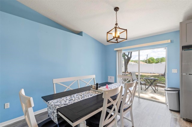 226 Pinegrove Dr, Palm Coast, FL 32164 - dining area featuring a chandelier, light wood-style floors, lofted ceiling, a textured ceiling, and baseboards