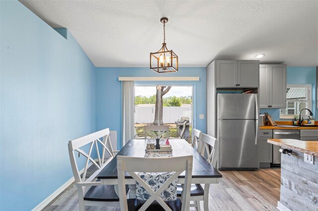 226 Pinegrove Dr, Palm Coast, FL 32164 - dining space with a chandelier, light wood-style flooring, a textured ceiling, and baseboards