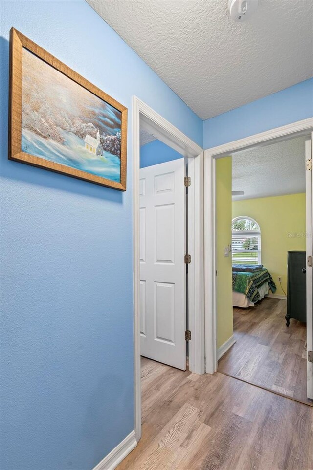 226 Pinegrove Dr, Palm Coast, FL 32164 - hallway featuring light wood finished floors, a textured ceiling, and baseboards