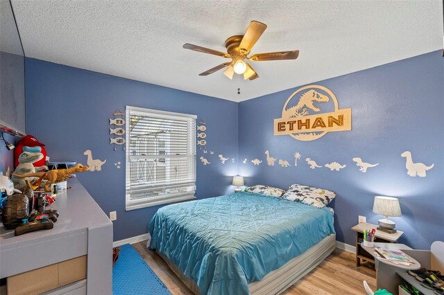 226 Pinegrove Dr, Palm Coast, FL 32164 - bedroom with wood finished floors, a ceiling fan, baseboards, and a textured ceiling