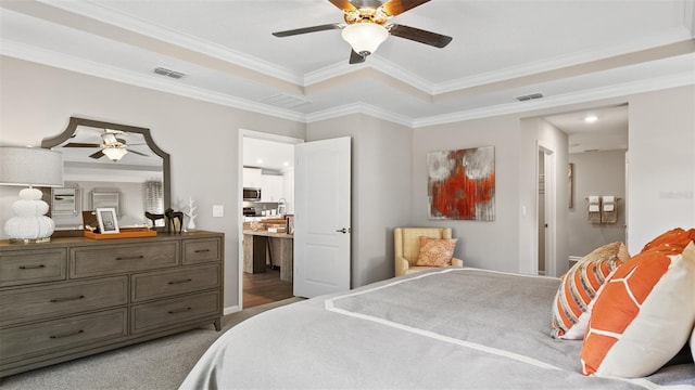 bedroom featuring connected bathroom, crown molding, a tray ceiling, and ceiling fan