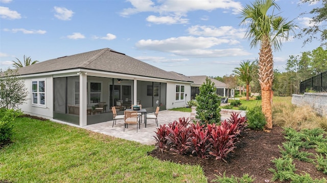 rear view of house with a sunroom, a yard, a patio, a shingled roof, and a ceiling fan