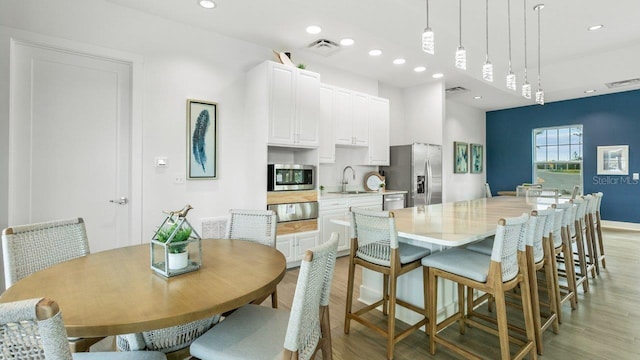 dining room featuring light wood-type flooring, recessed lighting, and baseboards