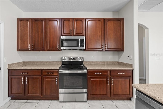 100 Point Pleasant Dr, Palm Coast, FL 32164 - kitchen with stainless steel appliances, arched walkways, light tile patterned floors, and light countertops