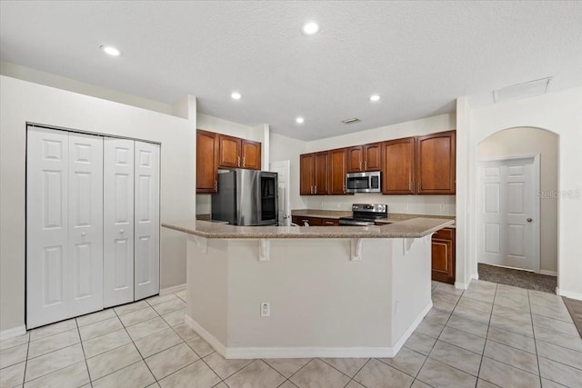 100 Point Pleasant Dr, Palm Coast, FL 32164 - kitchen with appliances with stainless steel finishes, light tile patterned floors, a kitchen bar, recessed lighting, and a spacious island