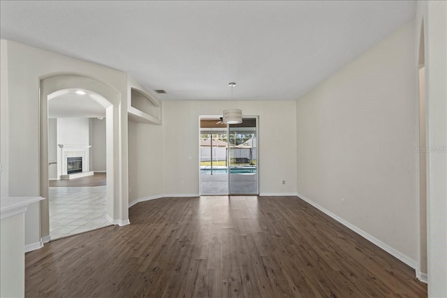 100 Point Pleasant Dr, Palm Coast, FL 32164 - empty room with dark wood finished floors, baseboards, a glass covered fireplace, and arched walkways