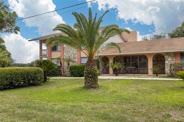 5009 Shore Dr, Saint Augustine, FL 32086 - view of front facade with stone siding, a front lawn, covered porch, and stucco siding