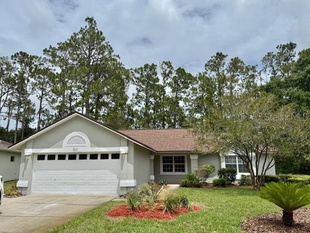 86 Ramblewood Dr, Palm Coast, FL 32164 - ranch-style home featuring an attached garage, concrete driveway, a front lawn, and stucco siding