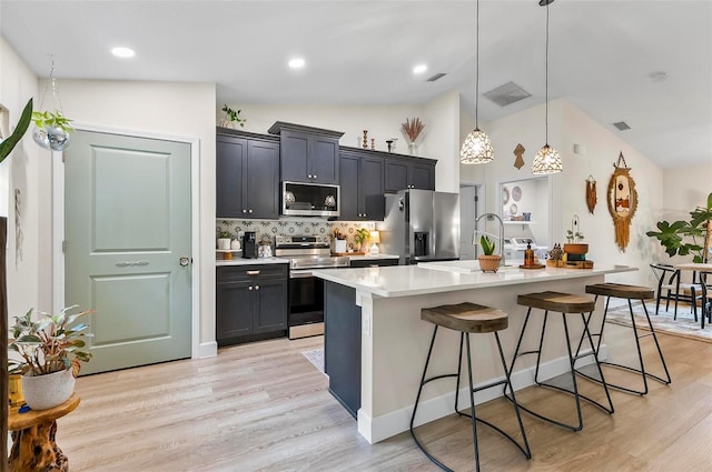 40 Biscayne Dr, Palm Coast, FL 32137 - kitchen with stainless steel appliances, light countertops, lofted ceiling, a breakfast bar area, and an island with sink