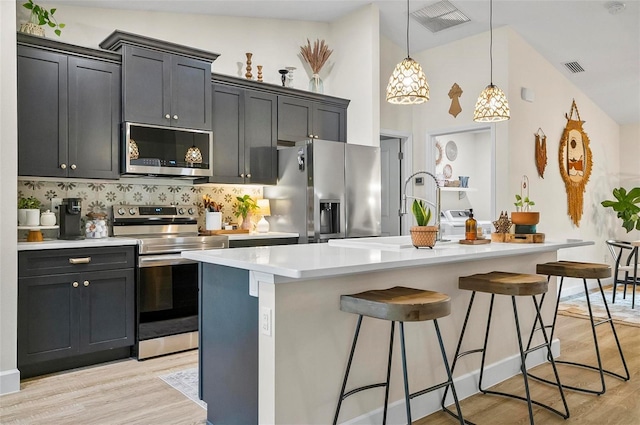 40 Biscayne Dr, Palm Coast, FL 32137 - kitchen featuring appliances with stainless steel finishes, light wood finished floors, light countertops, a center island with sink, and a breakfast bar area