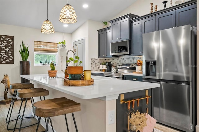 40 Biscayne Dr, Palm Coast, FL 32137 - kitchen with stainless steel appliances, a center island with sink, tasteful backsplash, a breakfast bar area, and light countertops