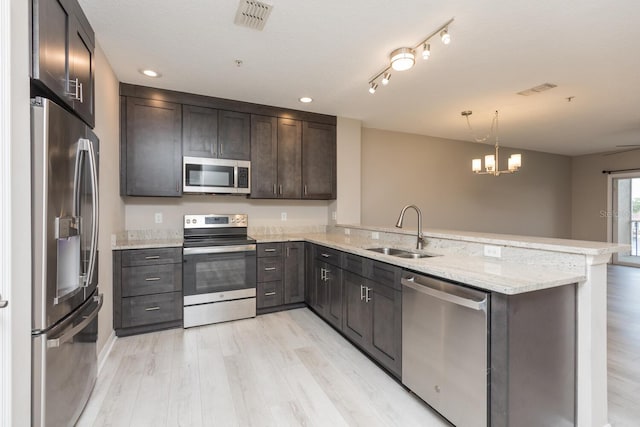 600 Canopy Walk Ln Unit 634, Palm Coast, FL 32137 - kitchen featuring stainless steel appliances, a sink, a peninsula, light wood finished floors, and light stone countertops