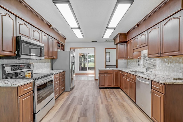 1466 Arena Rd, Fleming Island, FL 32003 - kitchen featuring stainless steel appliances, a sink, light wood-style floors, decorative backsplash, and light stone countertops
