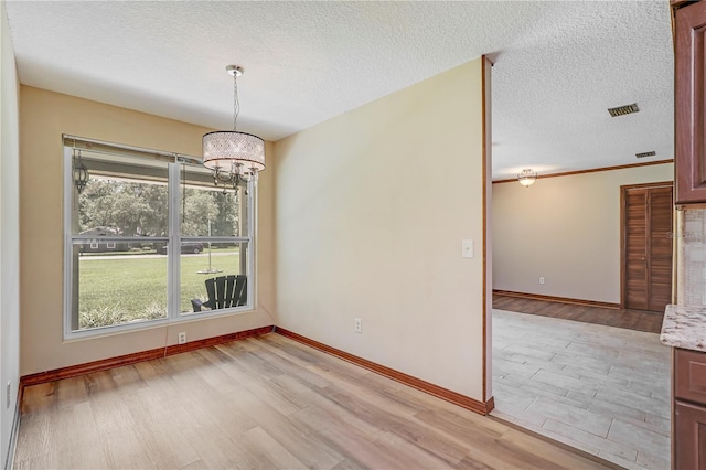 1466 Arena Rd, Fleming Island, FL 32003 - unfurnished dining area featuring light wood-style floors, a chandelier, a textured ceiling, and baseboards