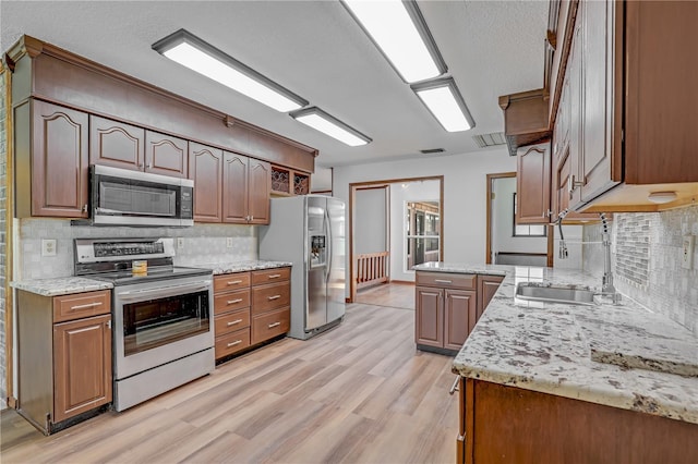 1466 Arena Rd, Fleming Island, FL 32003 - kitchen featuring stainless steel appliances, a sink, decorative backsplash, light wood-style floors, and a textured ceiling