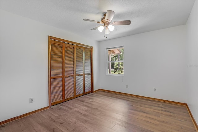 1466 Arena Rd, Fleming Island, FL 32003 - unfurnished bedroom featuring wood finished floors, baseboards, a closet, a textured ceiling, and ceiling fan