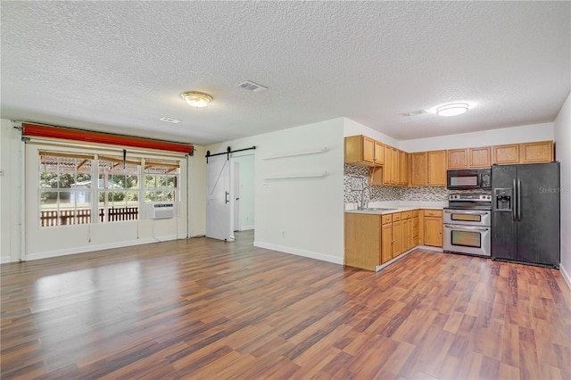 1466 Arena Rd, Fleming Island, FL 32003 - kitchen with black appliances, a barn door, wood finished floors, light countertops, and a textured ceiling