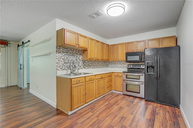 1466 Arena Rd, Fleming Island, FL 32003 - kitchen featuring black appliances, a sink, dark wood-style flooring, light countertops, and a barn door